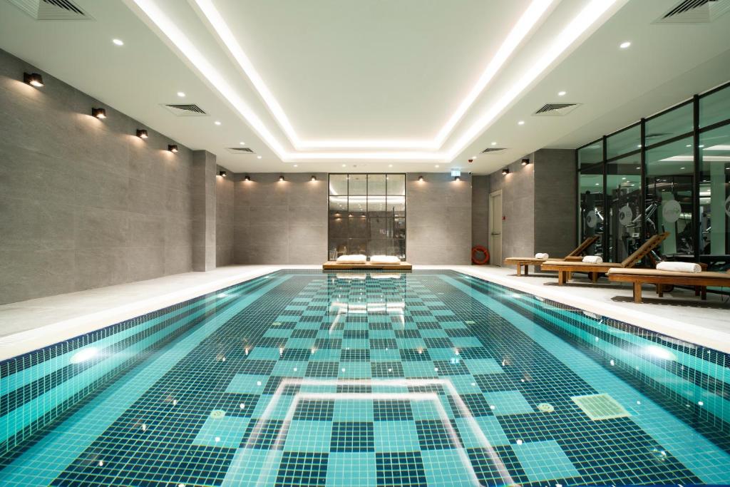 伊斯坦布尔Arts Hotel Taksim的一座铺有瓷砖地板的室内游泳池和一个游泳池
