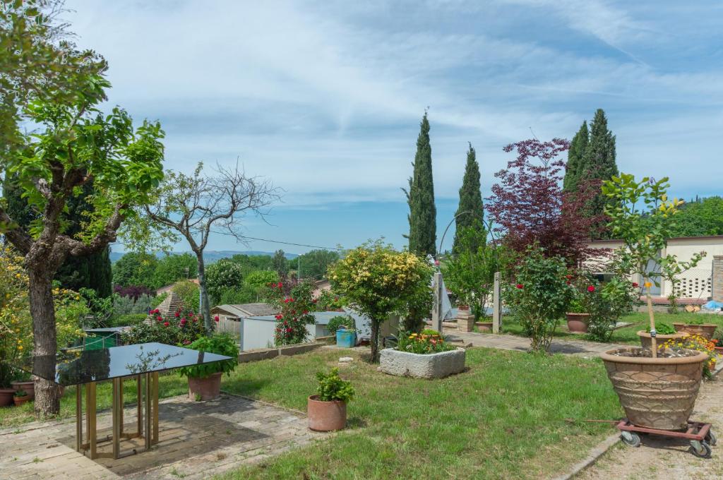阿西西Assisi Green Country Apt with parking & Netflix的花园,花园内有桌子和一些植物和树木