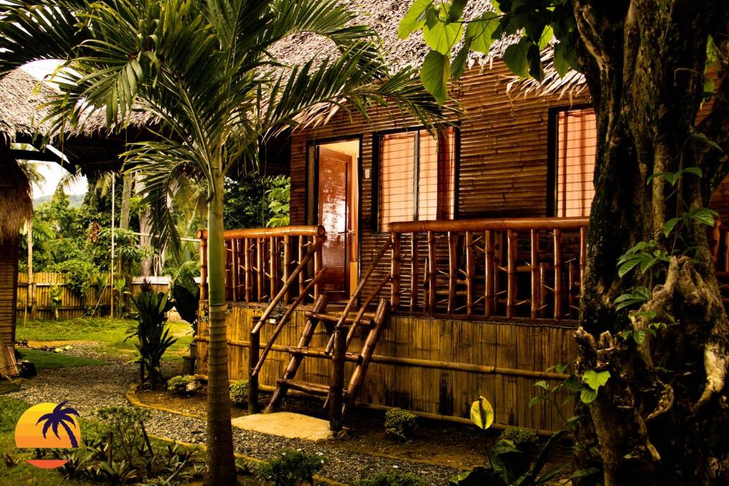 洛博克Loboc Cool River Resort的木屋设有门廊和椅子,位于外面