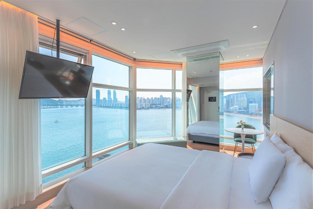 釜山Hotel Marine view的一间卧室设有一张大床、电视和窗户。