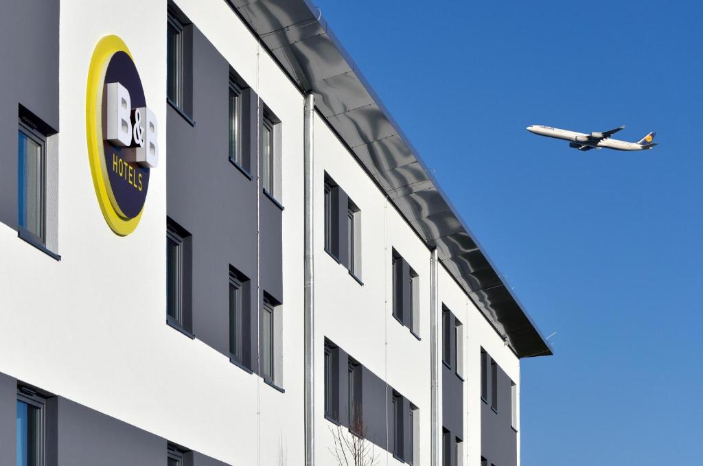 哈尔伯格摩斯B&B HOTEL München-Airport的飞机飞过与医院同住的大楼