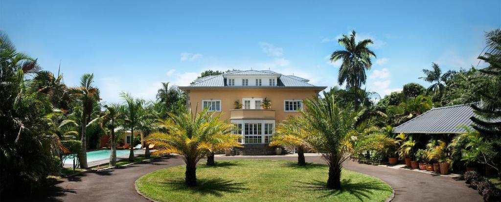 罗斯希尔Maison D’hôtes Coignet的一座棕榈树大房子前面