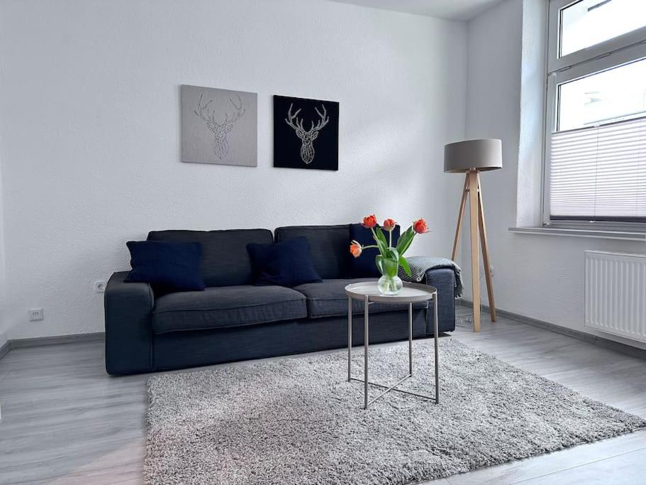 赫恩Möblierte EG- Wohnung zentral in Herne mit Parkplatz,WLAN und Netflix的客厅配有蓝色的沙发和带鲜花的桌子