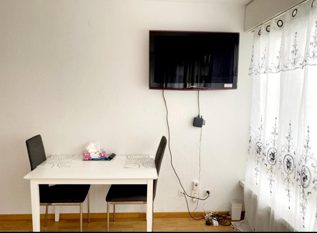 伯尔尼Kleine Wohnung im Zentrum Bern nähe Marzili的一张带两把椅子的白色桌子和墙上的一台电视