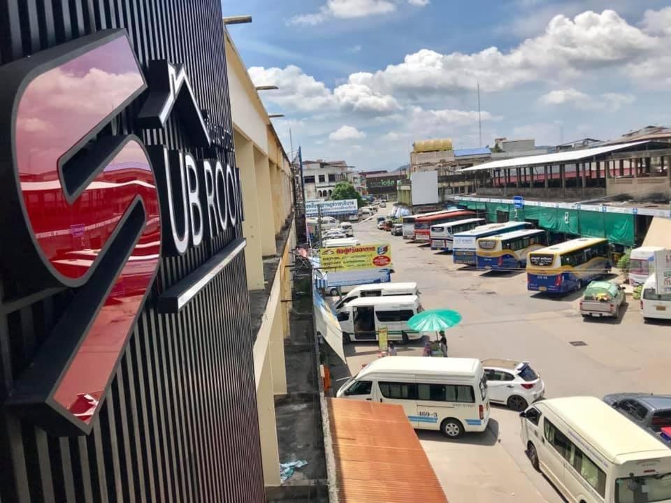 素叻ซับรูมโฮเทล Subroom Hotel的享有停车场的景色,停车场设有巴士和汽车