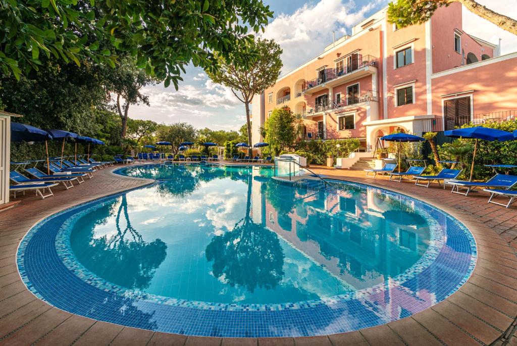 伊斯基亚圣华伦天奴泰尔梅酒店的一个带蓝色椅子和遮阳伞的大型游泳池