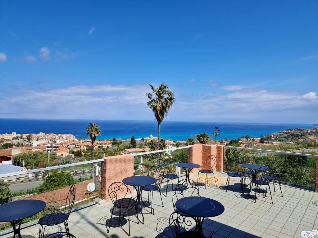 特罗佩阿Hotel - Giardino Marchese D'Altavilla的一个带桌椅的庭院和大海