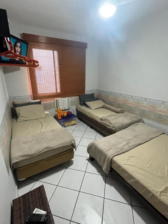 瓜鲁雅Nosso apê no Guarujá - Unidade Aquário的一间设有两张床和一张桌子的房间