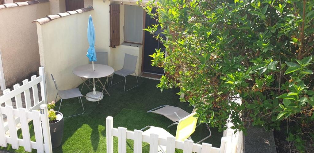 格雷乌莱班Maisonnette studio jardinet的庭院设有白色的围栏和桌椅。