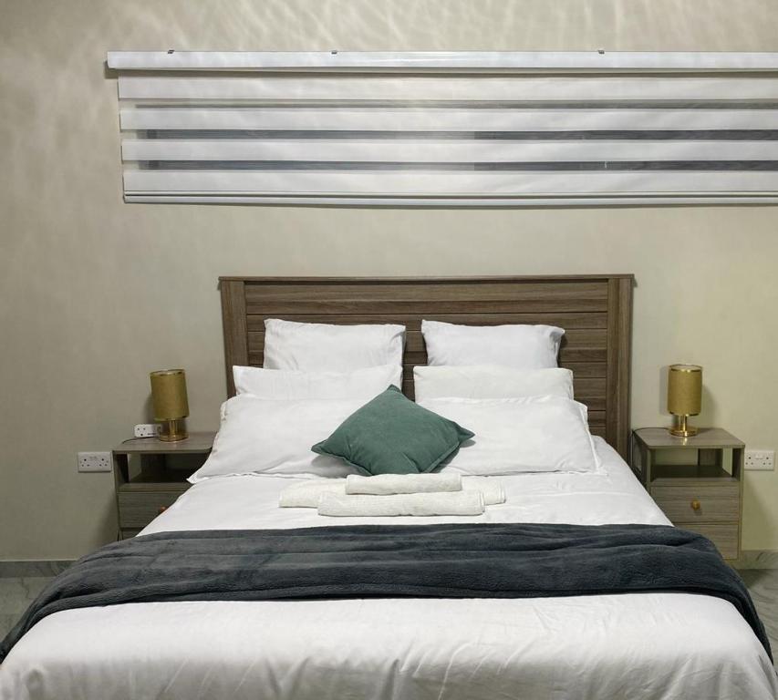 哈博罗内modern, two-story luxury house的一张配有白色床单和绿色枕头的大床