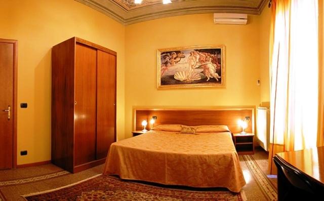 佛罗伦萨拉鲁娜宾馆的卧室配有一张床,墙上挂有绘画作品