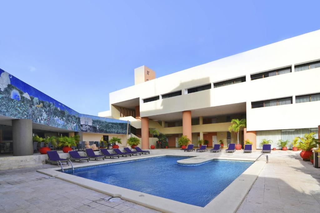 梅里达Hotel Los Aluxes的建筑前的一座带游泳池的建筑