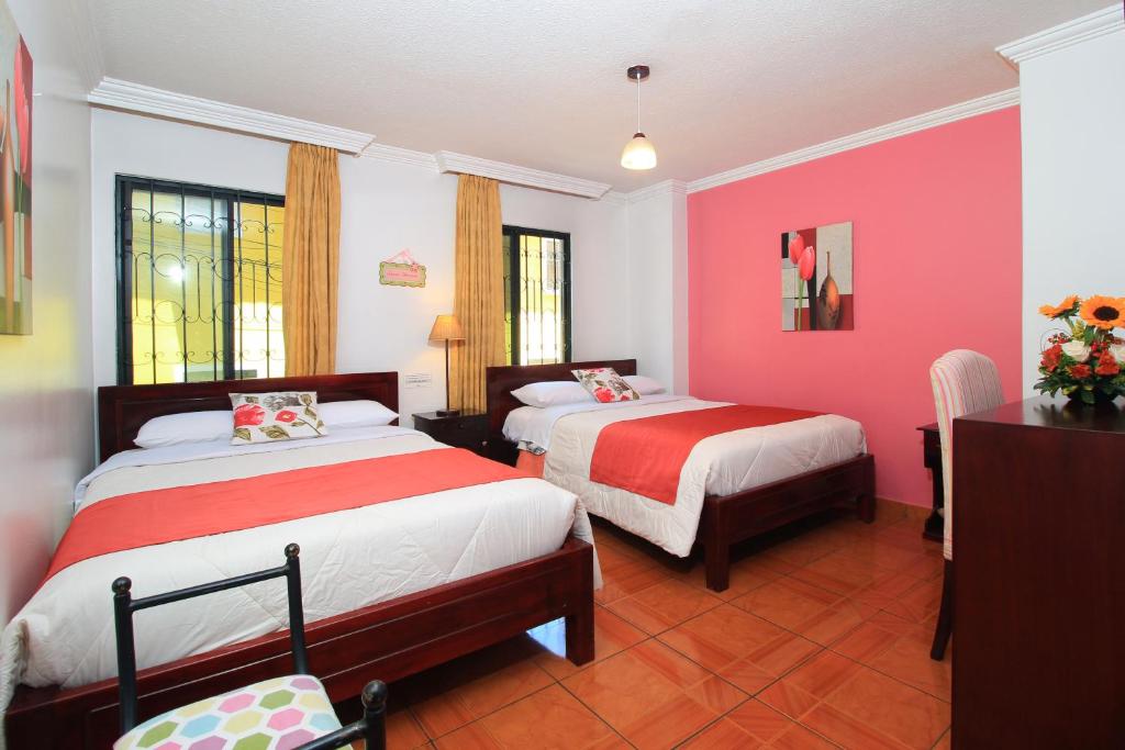 基多La Rosario的一间卧室设有两张床,墙壁粉红色
