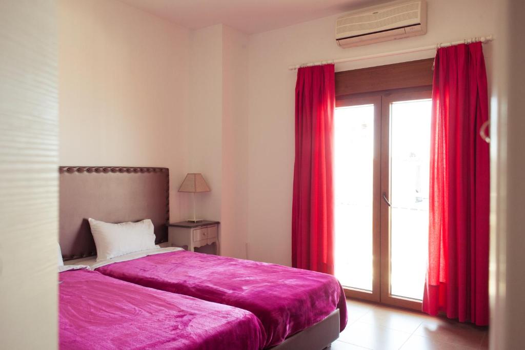 欧拉努波利斯Emmeleia Accommodation by Maria Riga的一间卧室配有床和红色窗帘的窗户