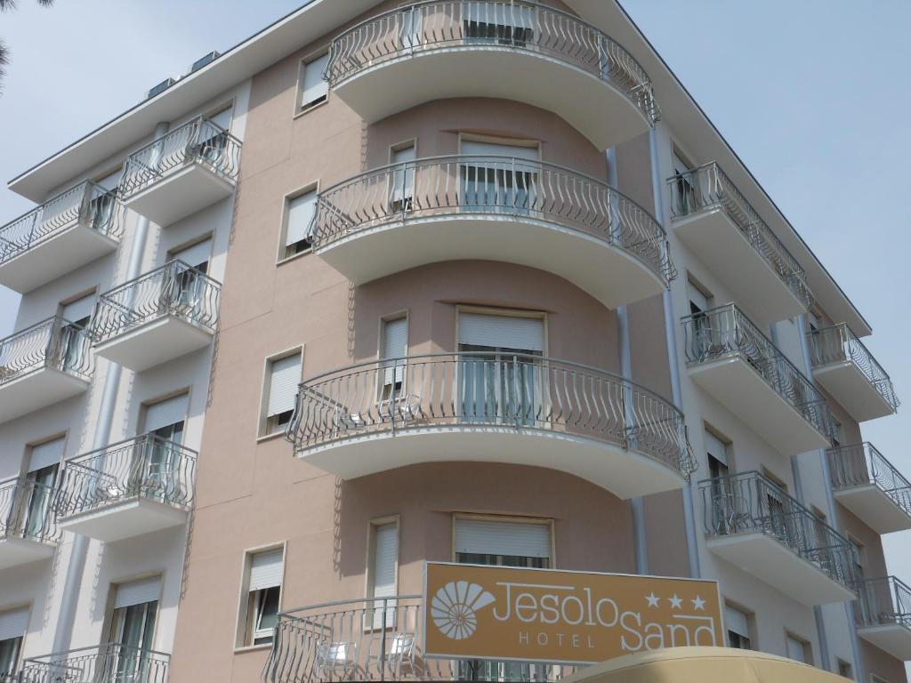利多迪耶索罗Hotel Jesolo Sand的带阳台的建筑,前面有标志