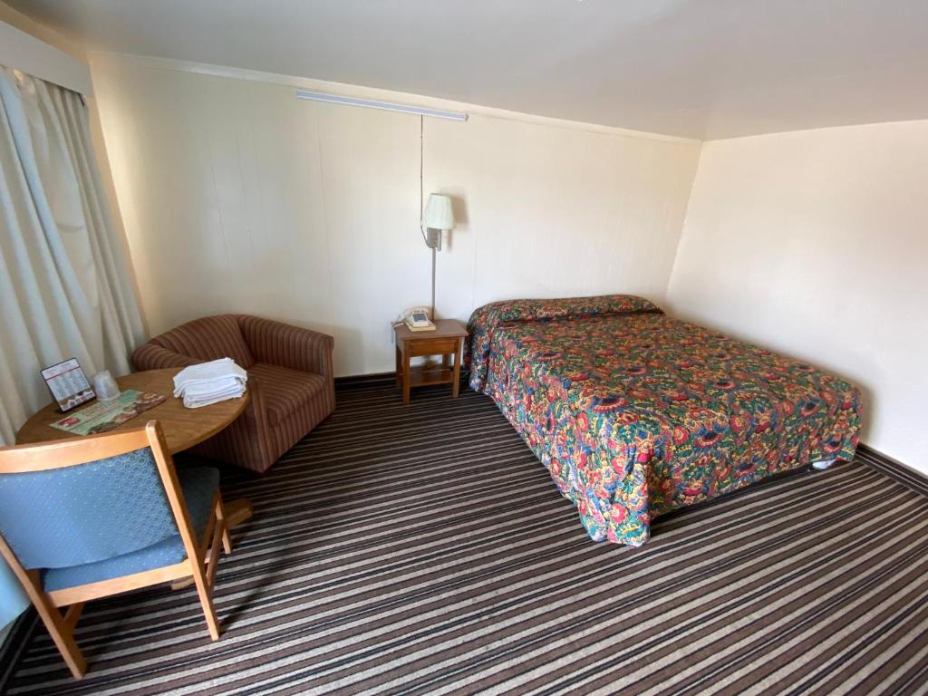 塔尔萨Western inn的酒店客房配有一张床、一把椅子和一张书桌