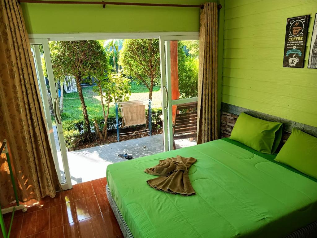 班柯木LUCKY Bungalows Koh Mook的一张绿色的床,位于带大窗户的房间里