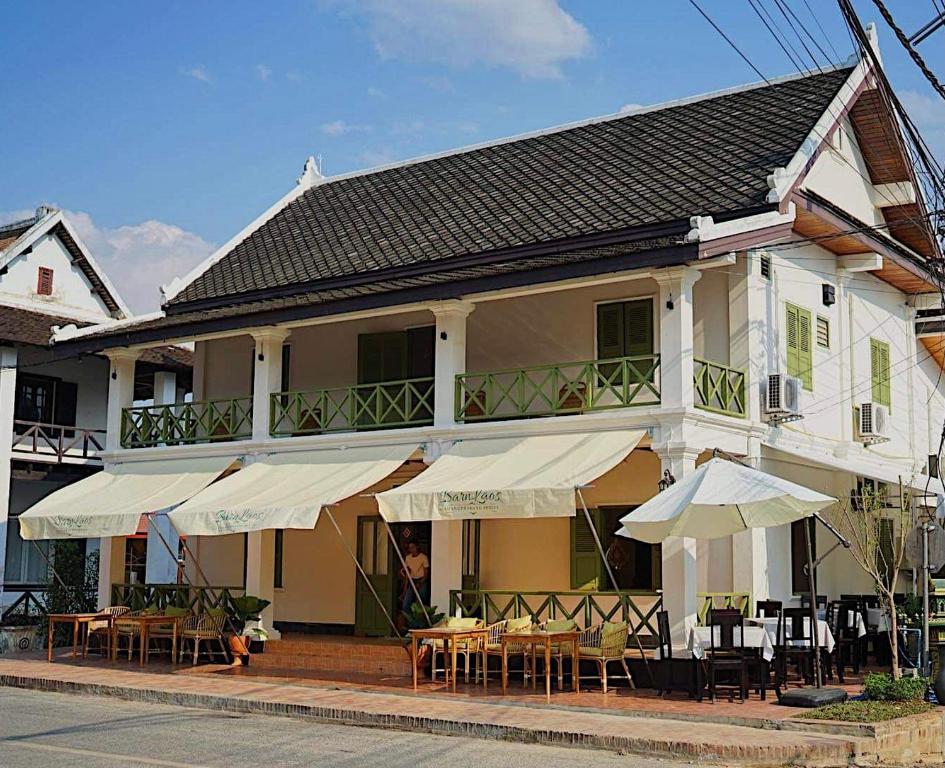 琅勃拉邦Barn Laos Luangprabang Hostel的前面有桌子和伞的建筑