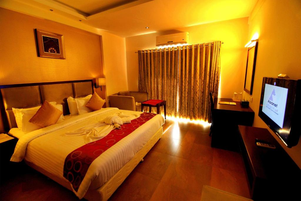 柴瑞海滩Paravoor Galaxy Hotel的酒店客房设有一张大床和一台电视。