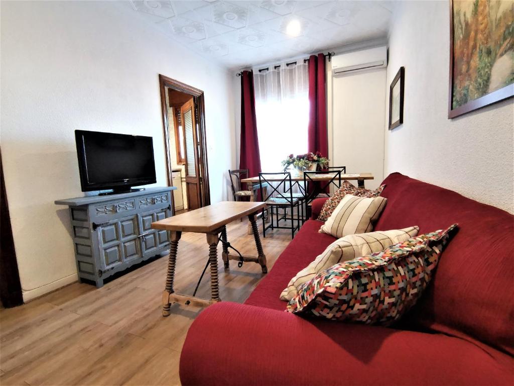 托莱多Casa Cervantes Toledo的客厅配有红色沙发和电视