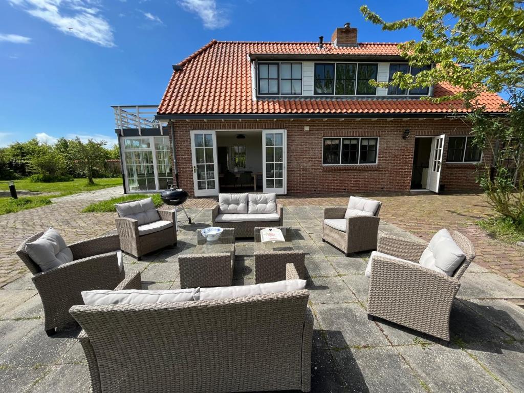 东卡佩勒Het Landhuis的房屋前设有带柳条椅和桌子的庭院。