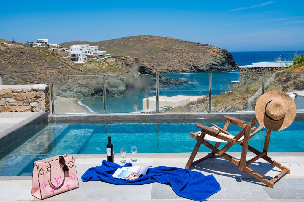 Merchia BeachMiramare Suites Mykonos的游泳池畔的椅子和一瓶葡萄酒