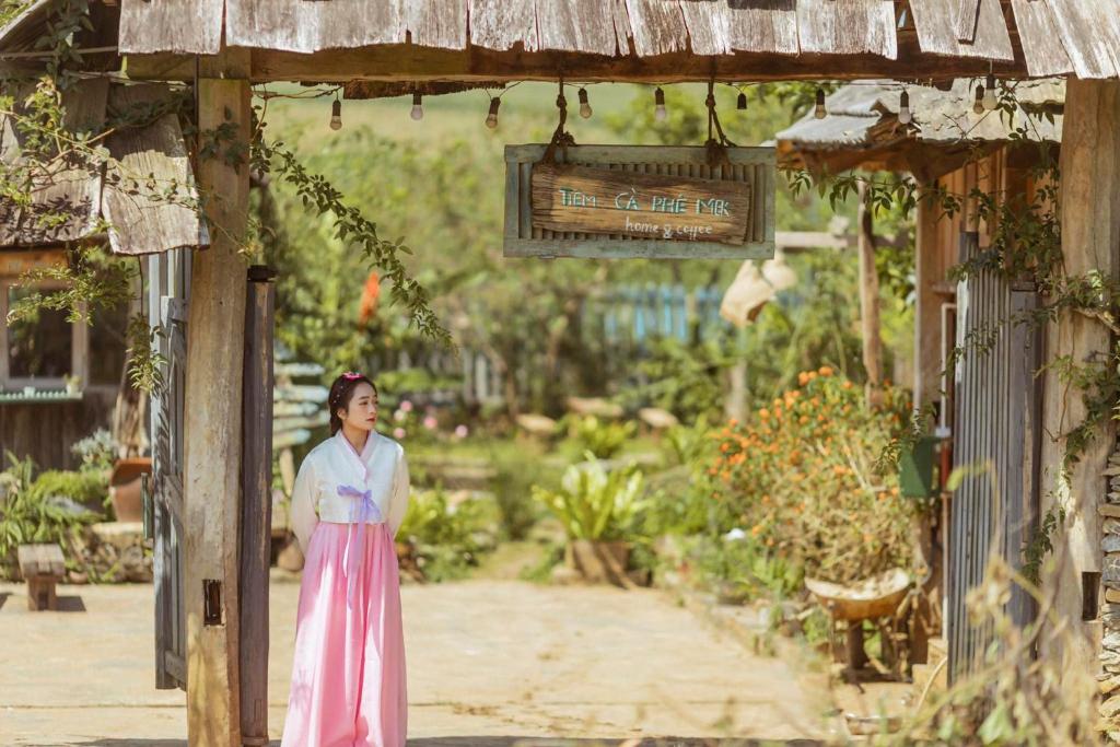 木州县Tiệm Cà Phê Mer Homestay & Coffee Mộc Châu的站在花园中的身着粉红色衣服的女人