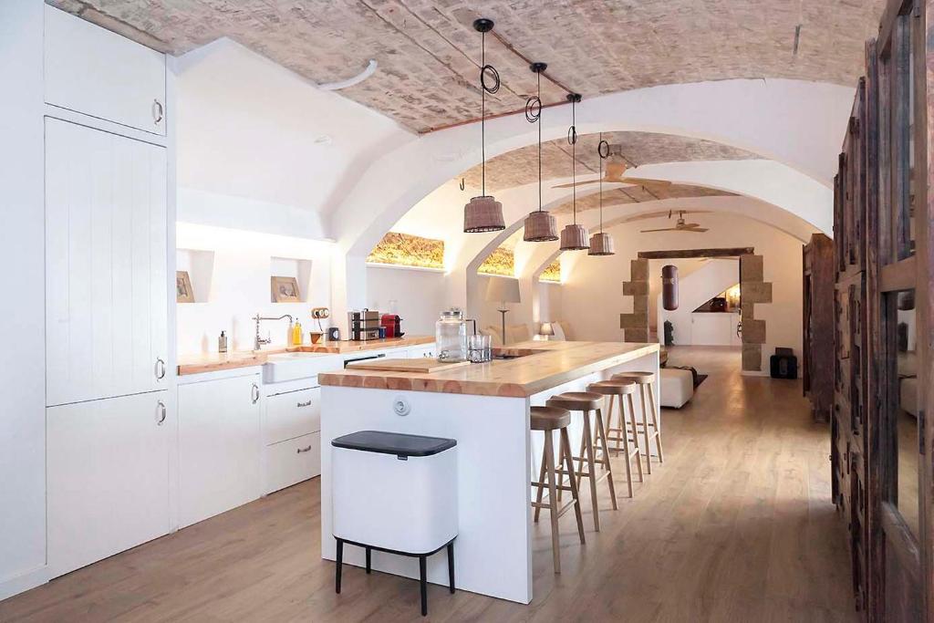 巴塞罗那A historic XVI century beach home near Barcelona的一间厨房,配有白色橱柜和一个带凳子的酒吧
