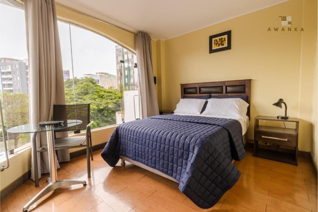 利马San Miguel Awanka Hotel的一间卧室配有一张床、一张桌子和一个窗户。