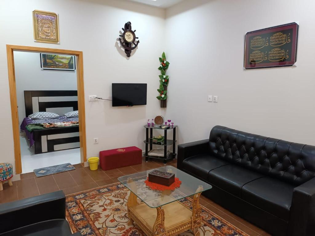 伊斯兰堡Islamabad Comfort Home的客厅配有黑色真皮沙发和桌子