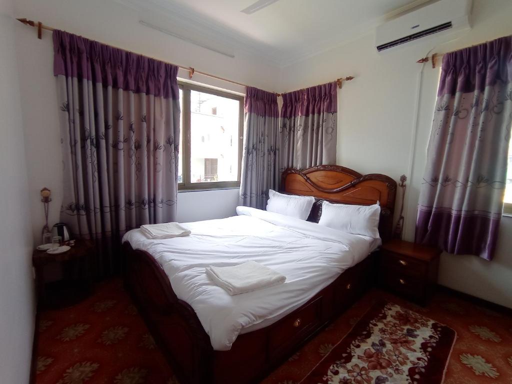 加德满都Janaki House的一间卧室配有一张带白色床单的床和一扇窗户。