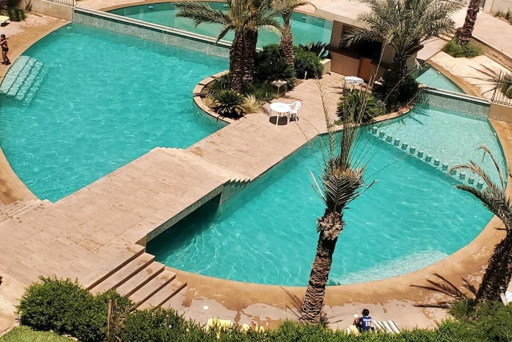 马拉喀什Marrakesh Pearl Gardens Amazing 2 Bedrooms apartment的享有游泳池的顶部景色,游泳池拥有棕榈树