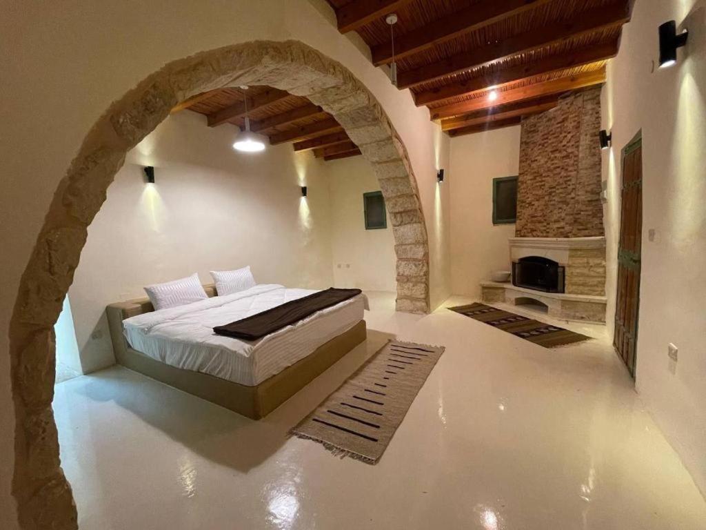 TufailahTafileh-Sila'a Heritage Village的一间带一张床铺的卧室,位于带拱门的房间