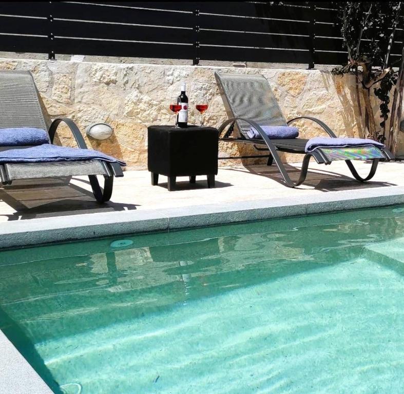 KatomérionVilla Iliogioma with private pool and sea view的游泳池畔的两把椅子和一张桌子