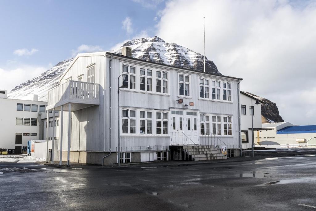 Bolungarvík茵纳斯舒思德旅馆的一座白楼,后面有雪覆盖的山