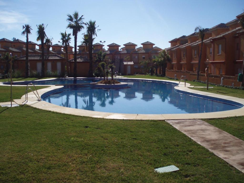 韦尔瓦Pinares de Lepe的棕榈树庭院里的一个大型游泳池