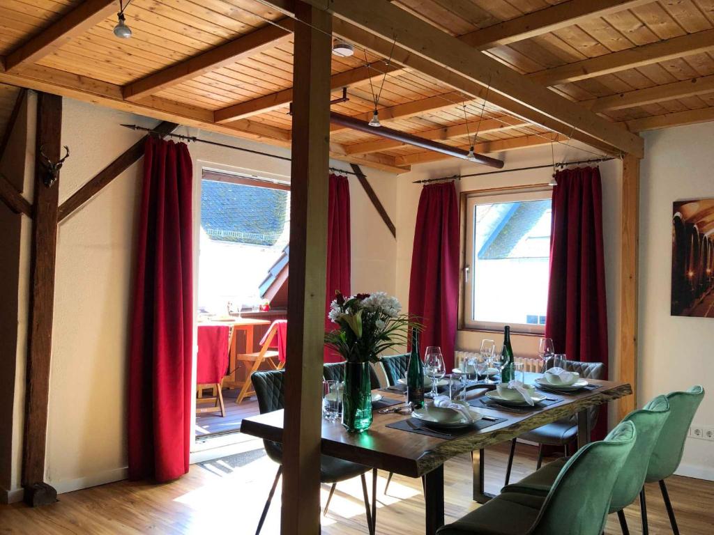 埃迪格尔-埃莱尔Ferienhaus-Am-Alten-Stadttor的一间设有长桌和红色窗帘的用餐室