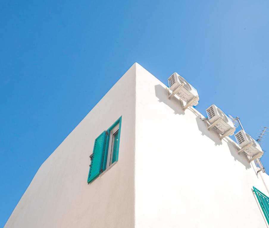阿桂拉斯La Casa Turquesa的白色的建筑,设有绿色的窗户,蓝天