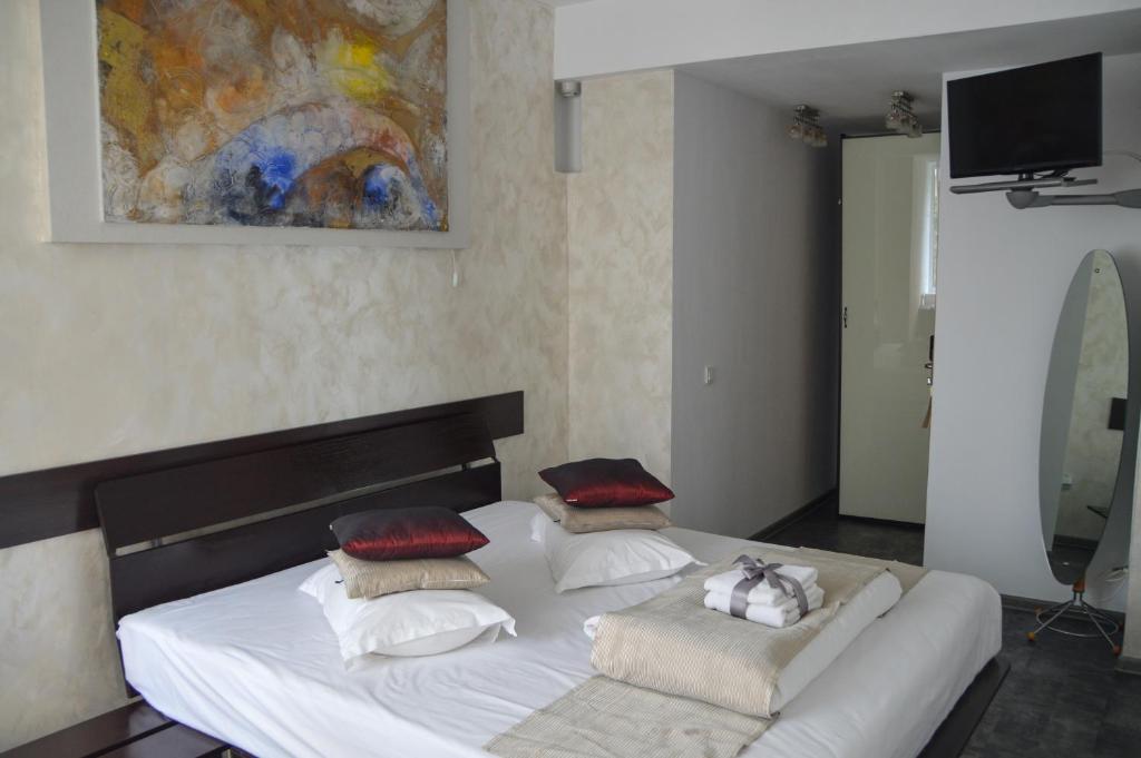 蒂米什瓦拉史迪威精品酒店的卧室配有带枕头的白色床和绘画。
