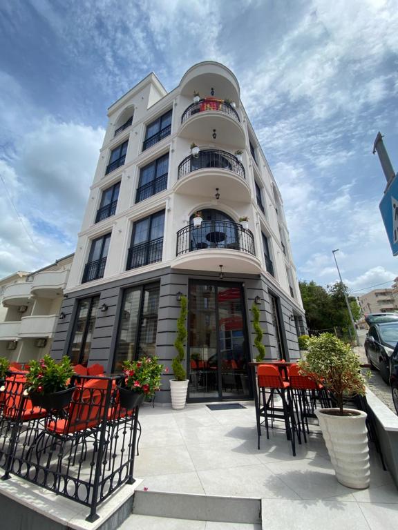 多布拉沃达Baba's Hotel & Spa的前面有红色椅子的白色建筑