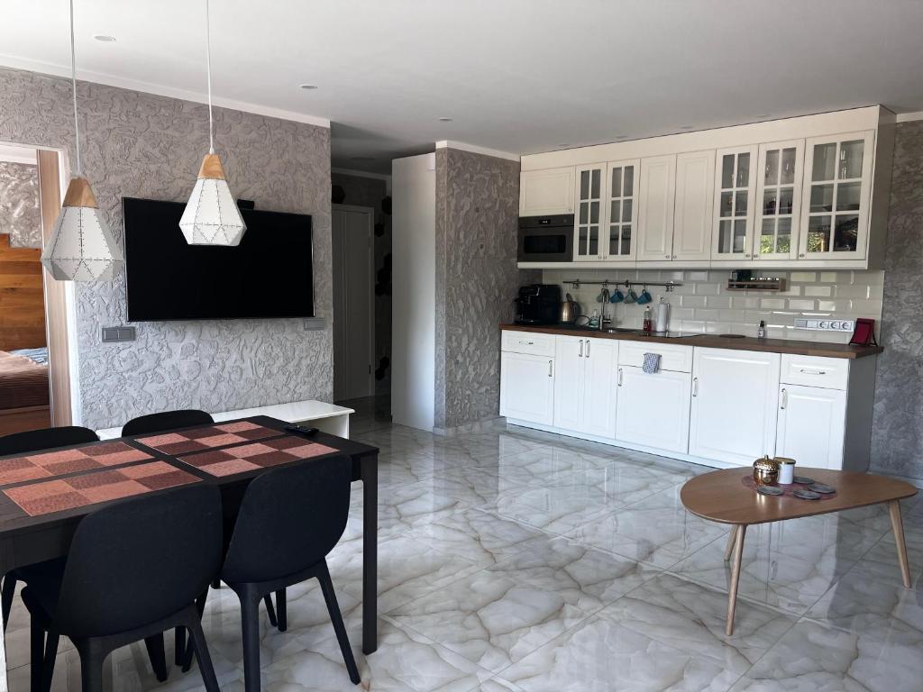 克雷廷加Rotušės apartamentai Kretingoje的厨房配有白色橱柜和桌椅