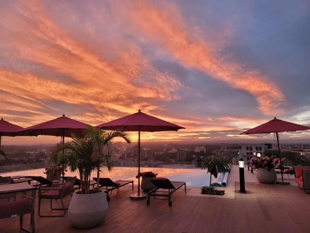 内罗毕Skynest Residences by Lisa's Paradise A的一个带桌子和遮阳伞的屋顶露台,享有日落美景。