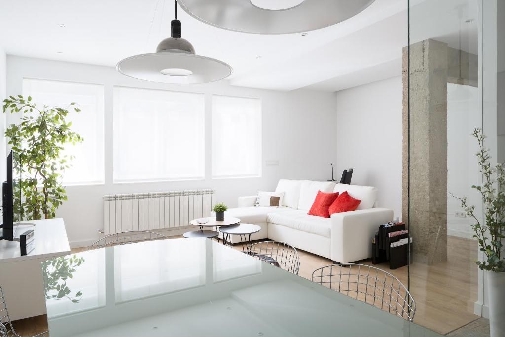 潘普洛纳CARPE DIEM - Disfruta a lo grande的白色的客厅配有白色的沙发和红色的枕头。