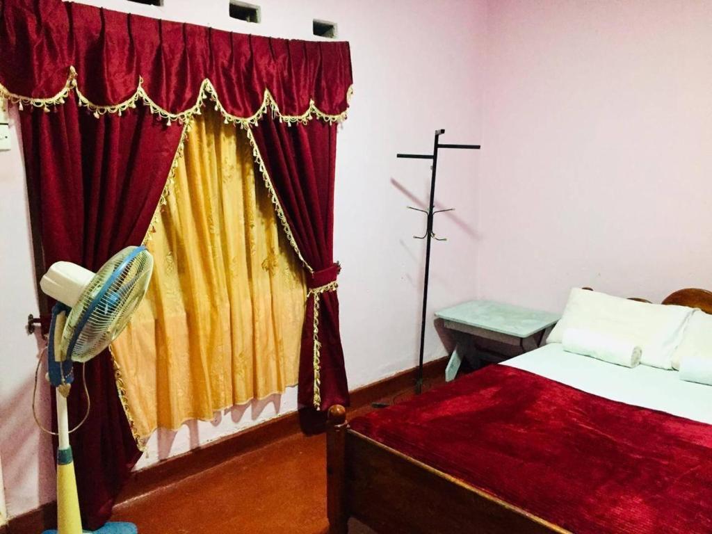 凯格勒AMBALAMA HOSTEL的一间卧室配有一张红色和黄色窗帘的床