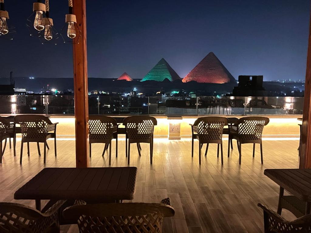 开罗Celia Pyramids View inn的一间晚上设有桌椅和金字塔的餐厅