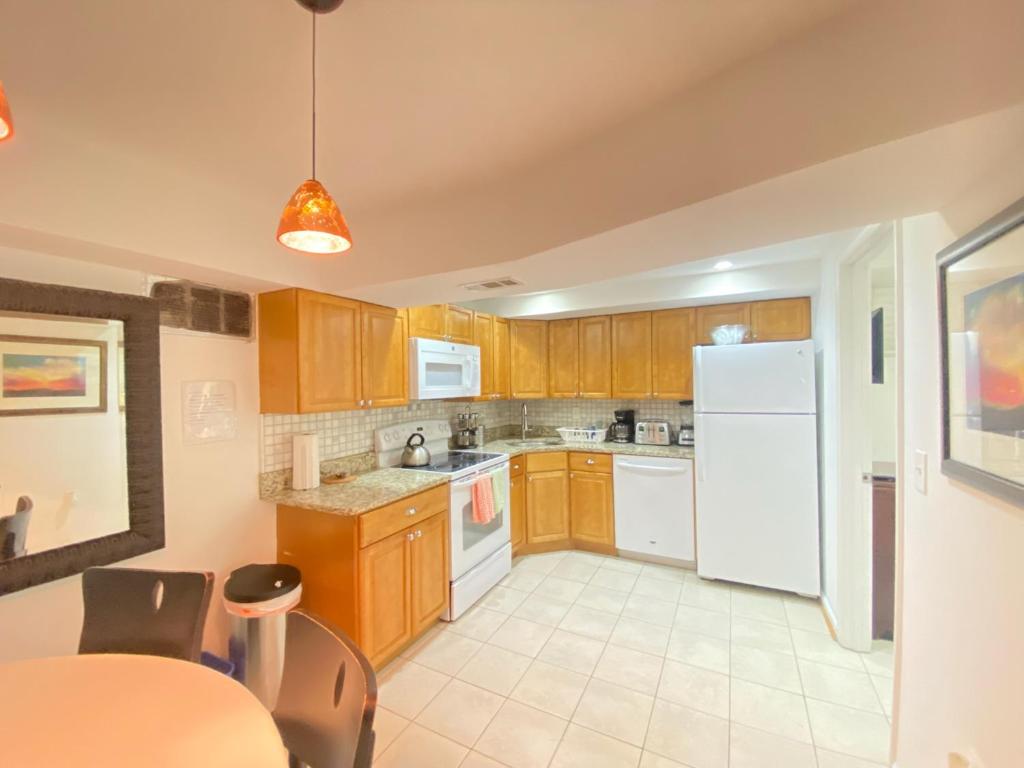 华盛顿COMFY Basement Home 2 Bdrm1Den 3Queen Beds的厨房配有木制橱柜和白色冰箱。