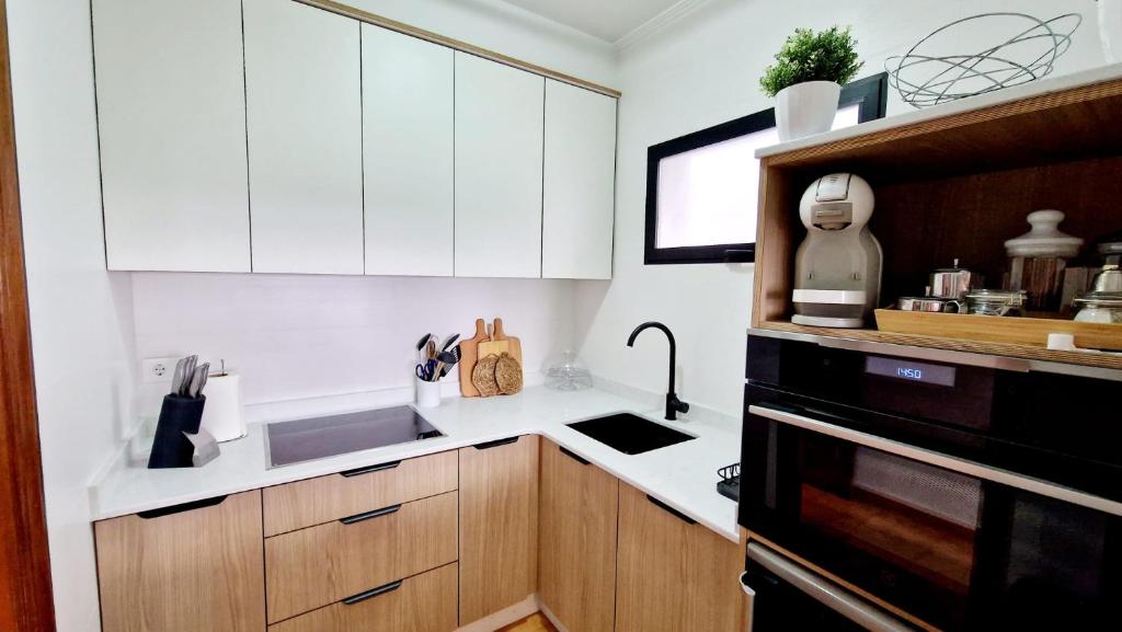 布埃乌Apartamento CARBALLEIRA的厨房配有白色橱柜和水槽