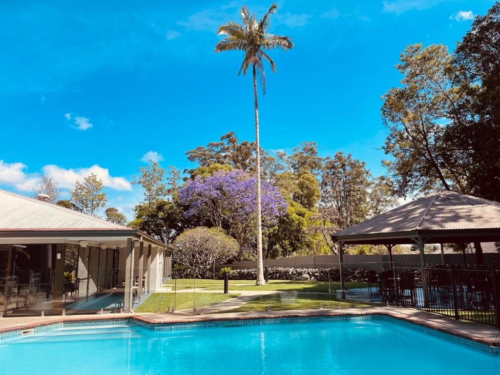 GoonellabahInvercauld House的棕榈树,在一座带游泳池的房子前