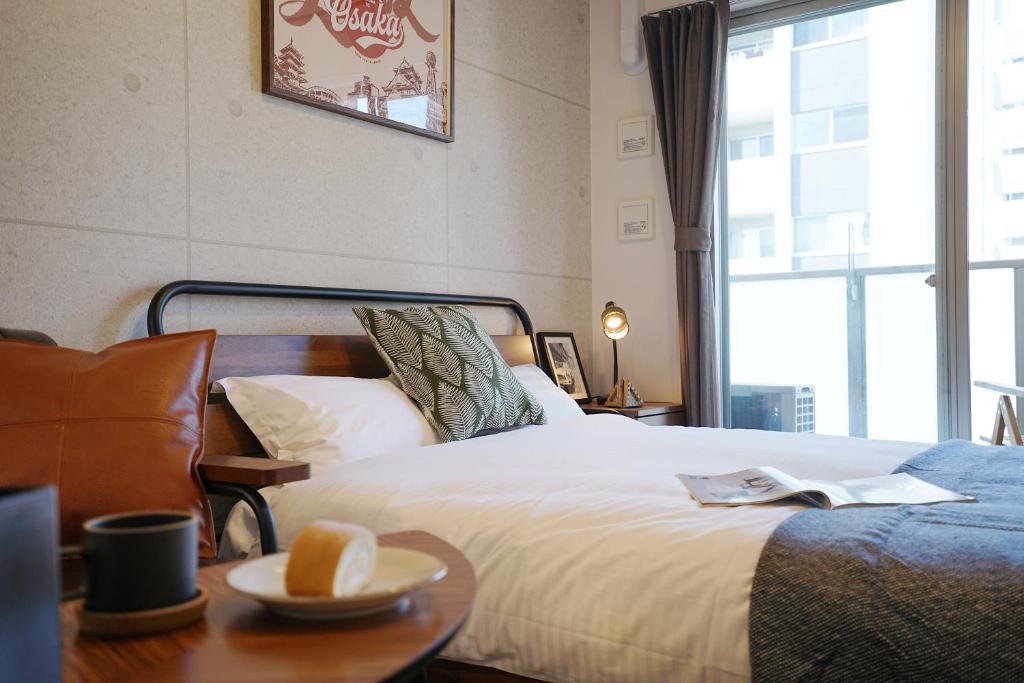 大阪川HOUSE黒門的一间卧室配有一张床和一张桌子,上面放着碗