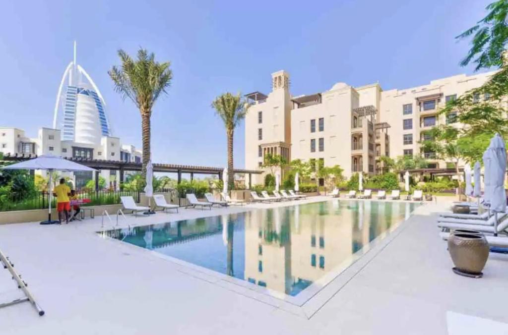 迪拜Madinat Jumeirah Living, MJL Dubai的棕榈树和建筑的酒店游泳池